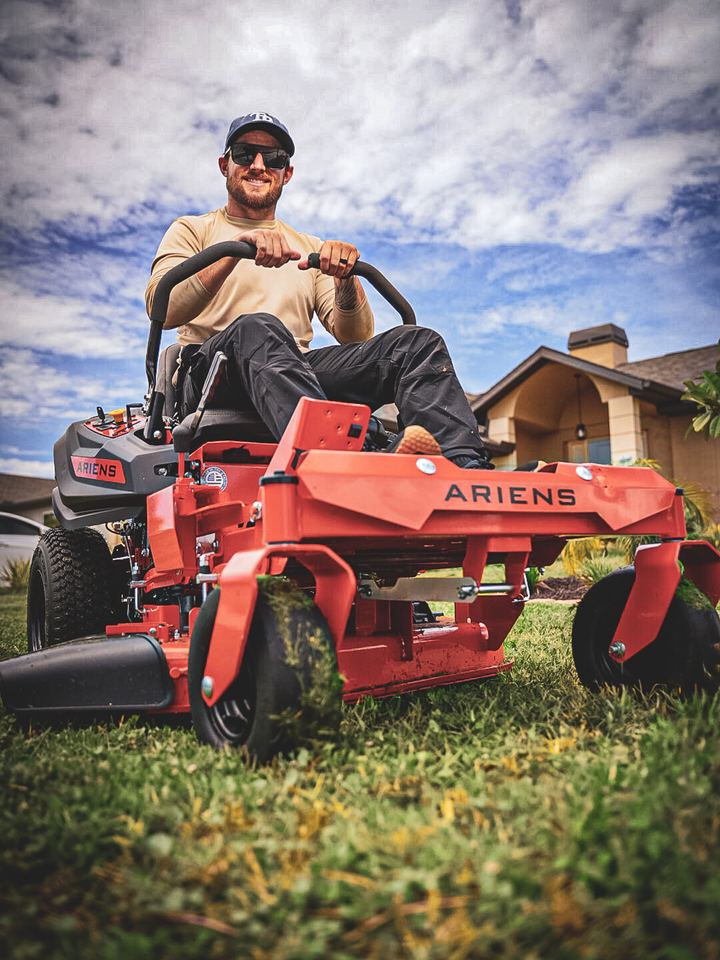 Owner driving a zero turn mower toward the camera