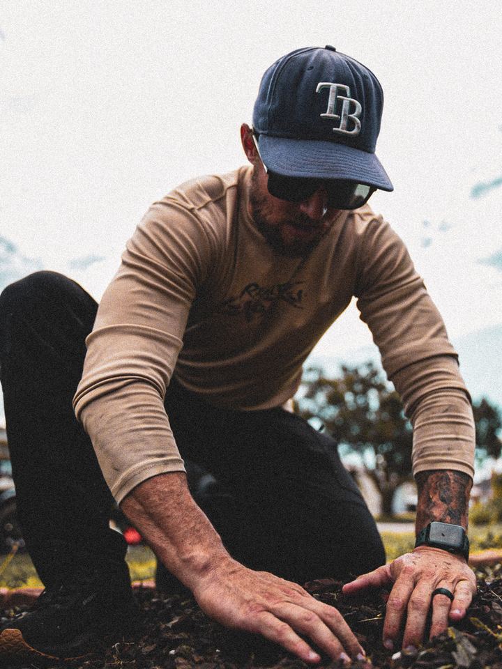 Crew member kneeling, working soil by hand